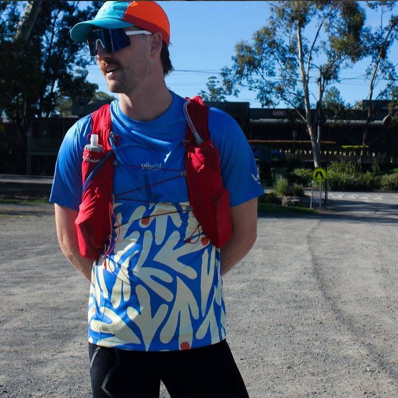 Man wearing Wippet Coconut Cool Everyday Running Shirt that is breathable, sweat wicking, ultra light-weight and UPF50+ sun protection for running, smiling during a trail run.