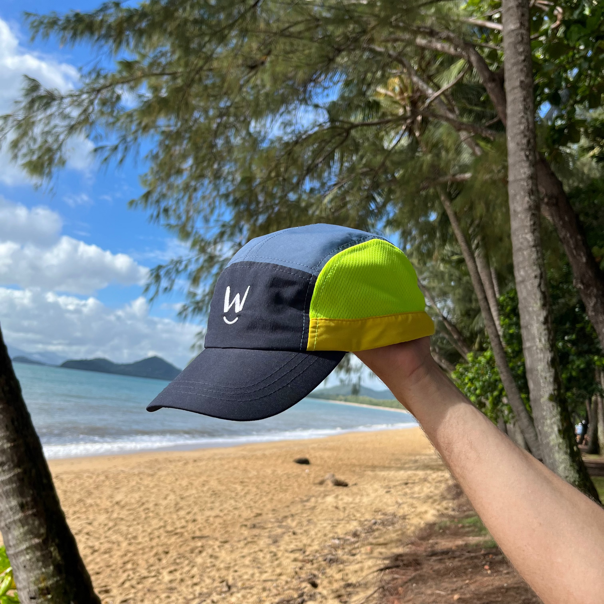 Wippet Running Cap Thunder Bolt – Lightweight, breathable cap with moisture-wicking technology, adjustable strap, sun protection, and bold design featuring dark tones with fluorescent lime yellow highlight at beach.