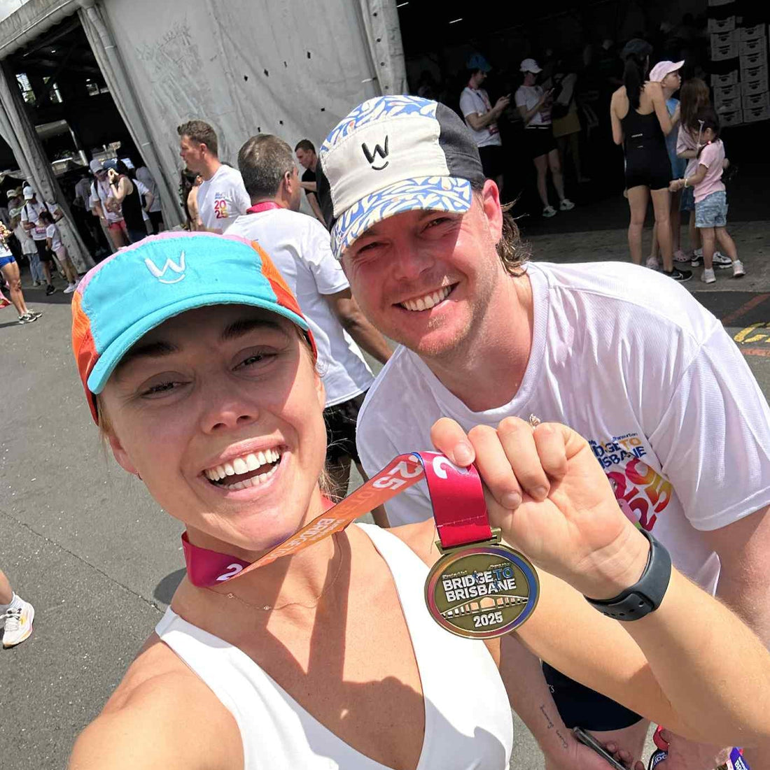 Runners taking a selfie with a race medal at bridge to Brisbane Marathon while wearing a Wippet Running Cap.