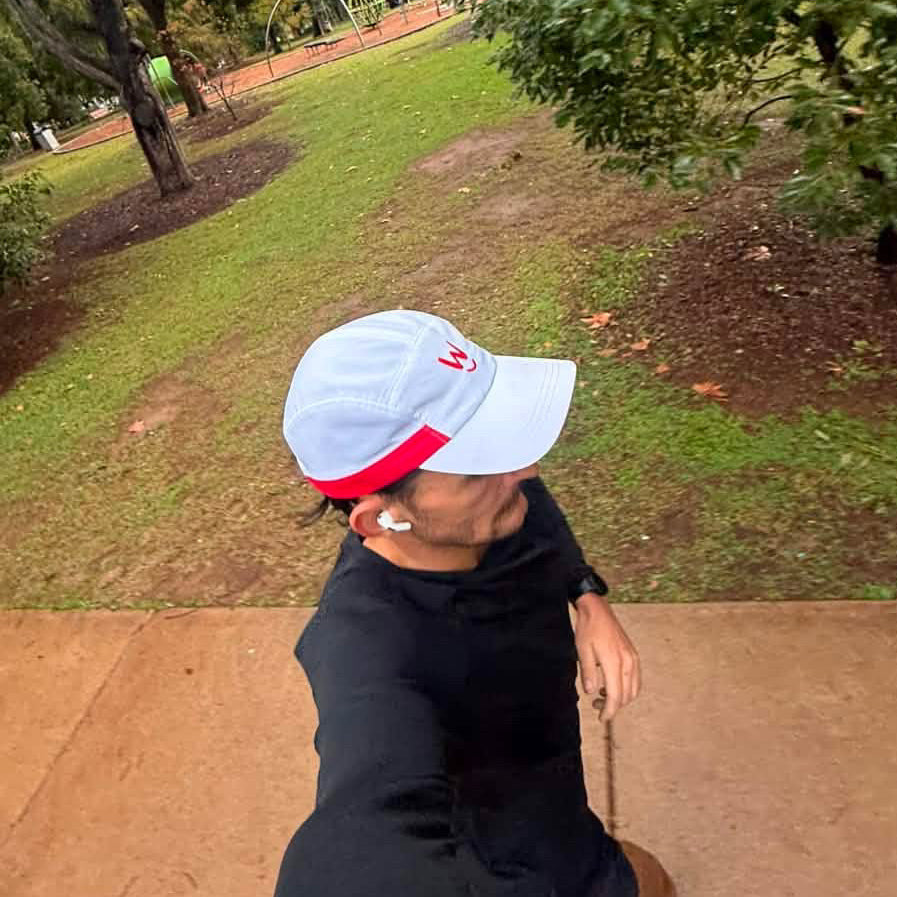Man running in the park wearing Wippet's breathable, sweat wicking, ultra light weight, sun protective Redline running cap.