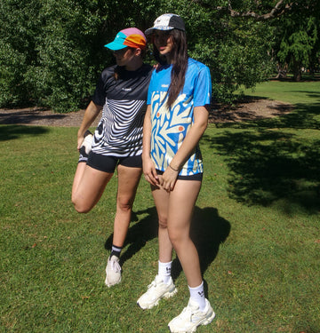 Two women runners wearing Wippet lightweight running tees and running caps with UPF50+ sun protection and moisture-wicking technology